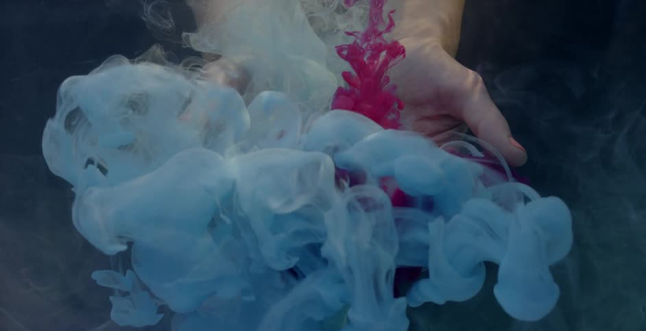Woman's hands hold blue colored foam as red liquid pours down