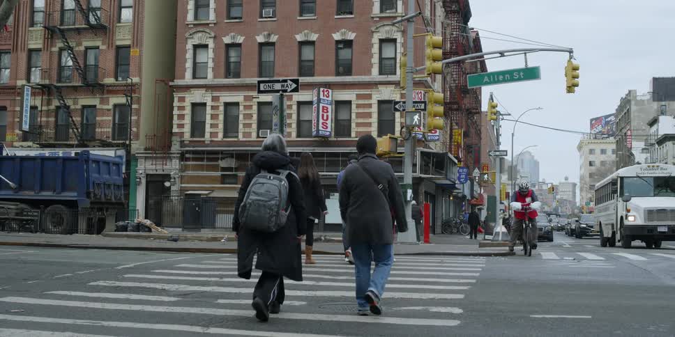 Pedestrians cross the street as traffic waits
