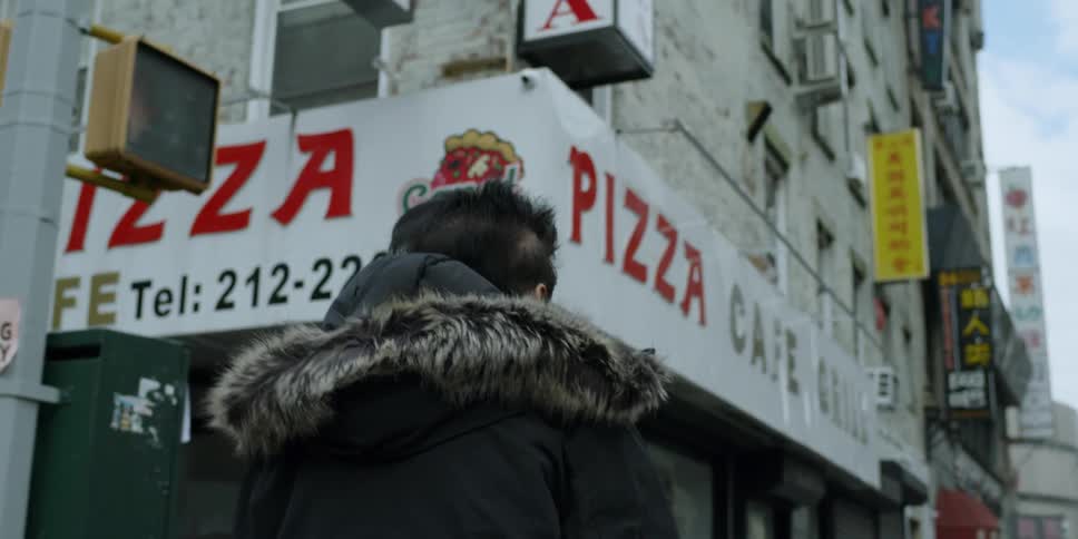 Man in a hooded jacket walks down the sidewalk