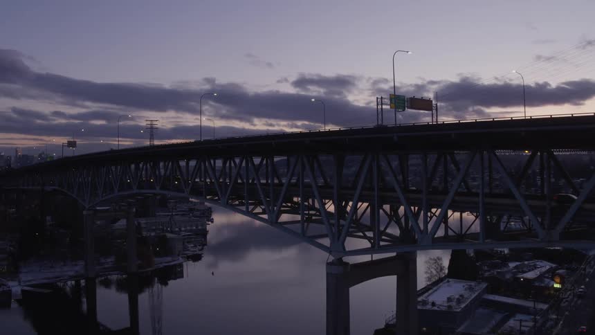 Ascent from the U District neighborhood over evening traffic on the Ship Canal bridge to reveal downtown Seattle in the distance