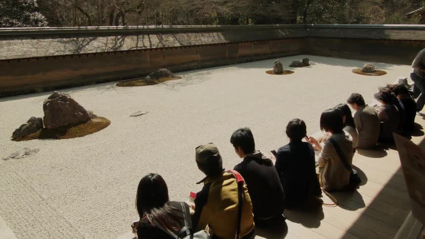 People sit on a wall in a zen garden on a sunny day
