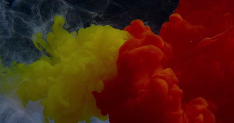 Clouds of red and yellow dye expand over white in liquid
