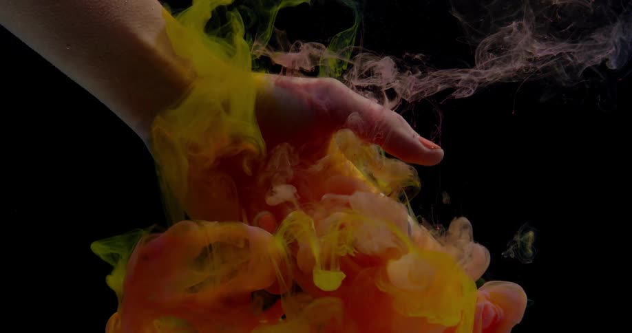 A person reaches into the water to touch the cloud of ink