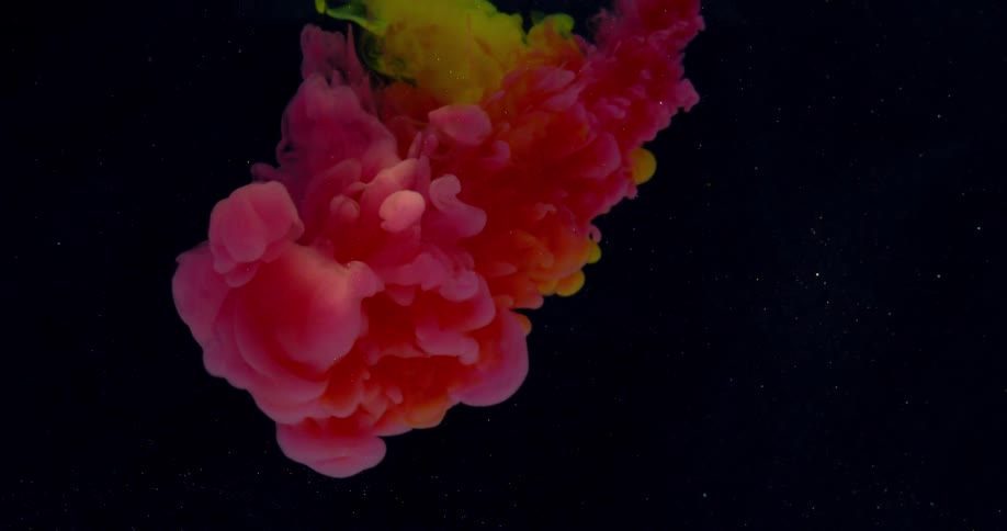 Clouds of red and yellow dye float and expand in liquid