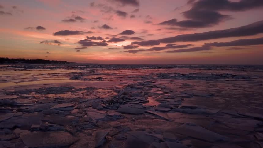 The sun sets over an icy lake