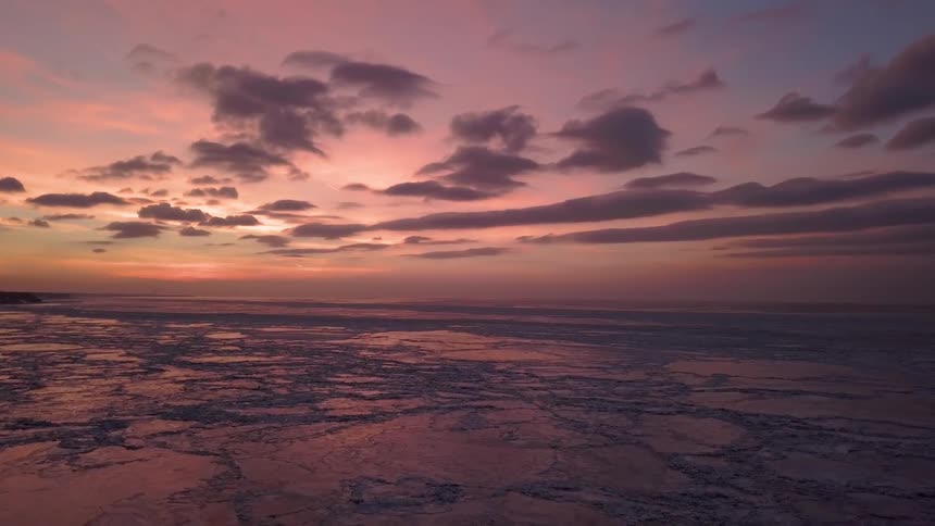 Clouds hanging in the sky above the frozen lake at sunset