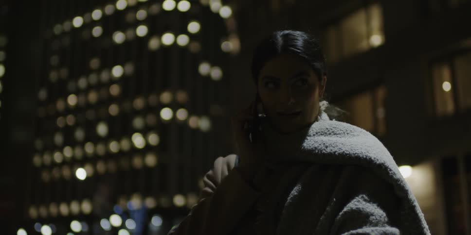 A woman talks on her phone at night in the city