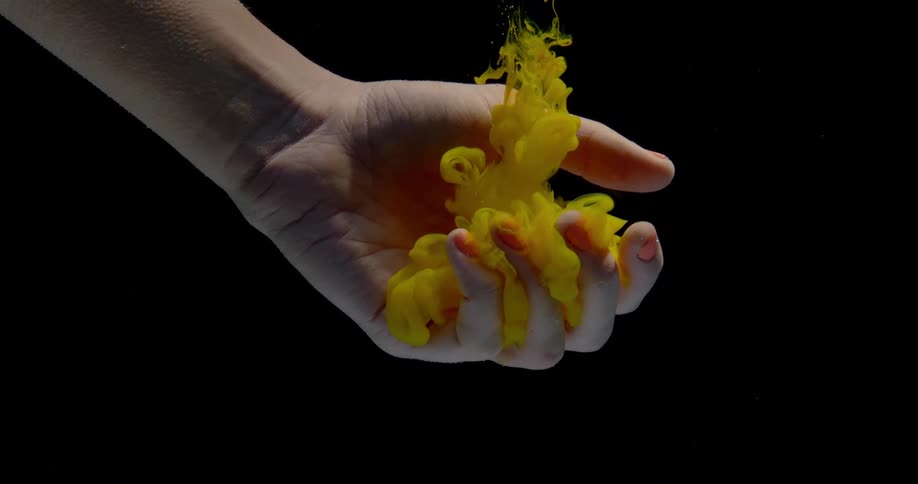 Clouds of dye float down into the palm of a submerged hand