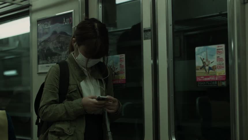 A woman wears a face mask on a subway train
