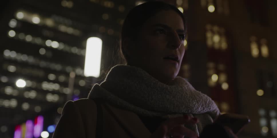 A woman is checking her phone in front of a building
