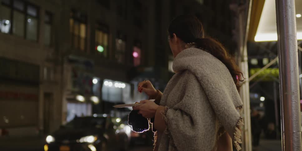 Woman chews food as she stands on the sidewalk