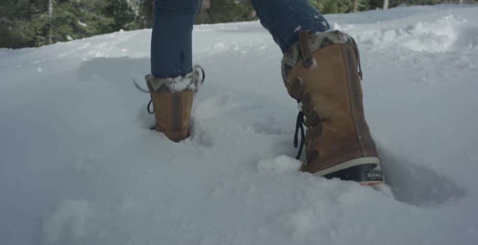 Woman wearing boots walks through the deep snow