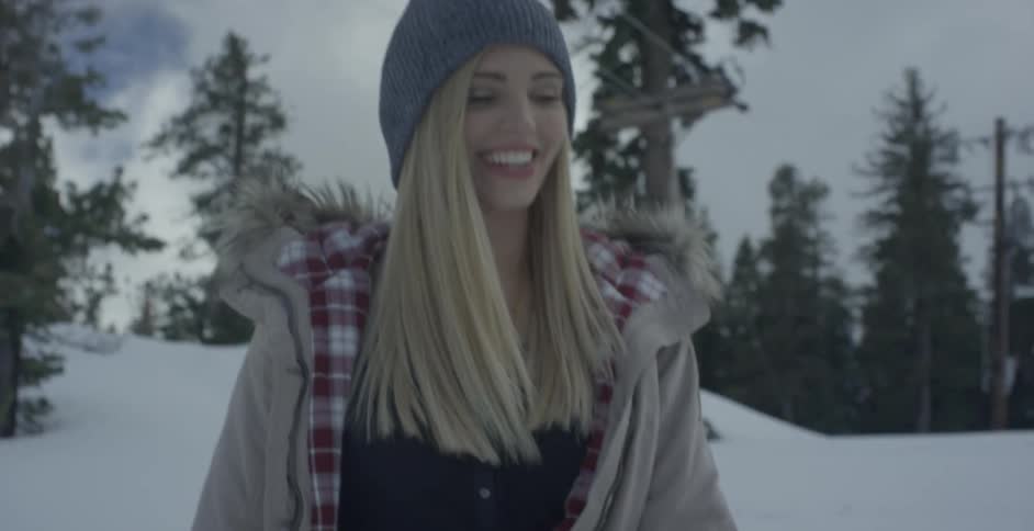 A woman smiles while walking in a snowy forest