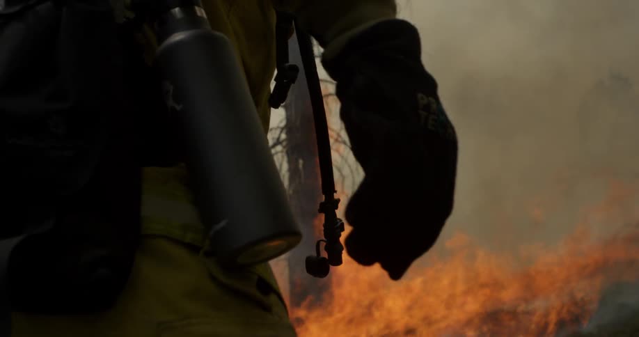 Man with equipment walks near a forest fire