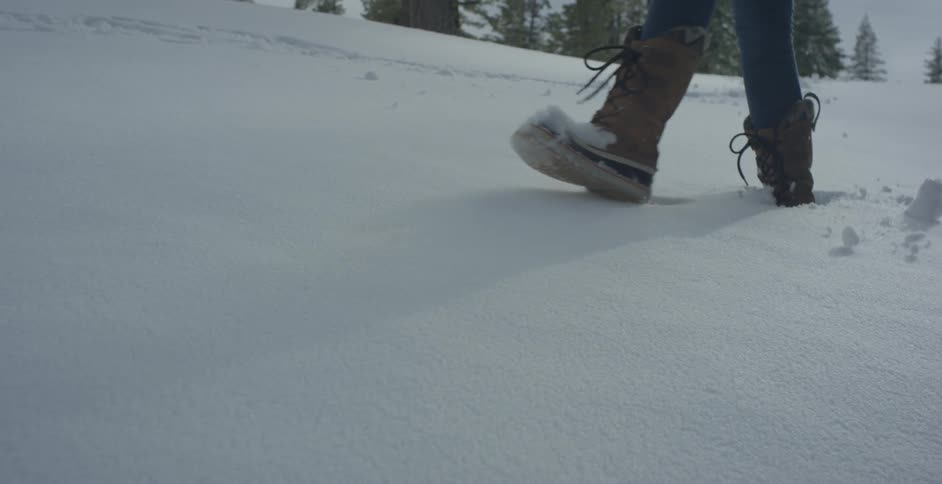 Person walks through the snow in tall boots