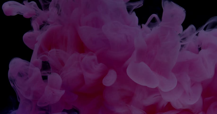 Pink liquid curls and floats in water with light shining on it