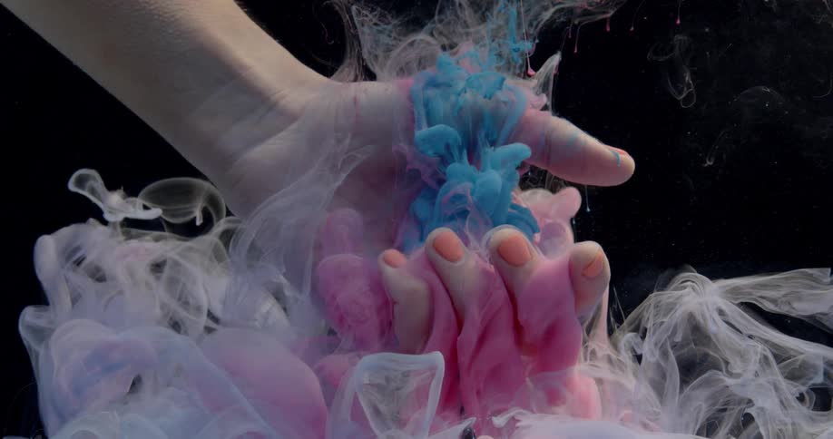 Clouds of dye float down into a woman's submerged hand