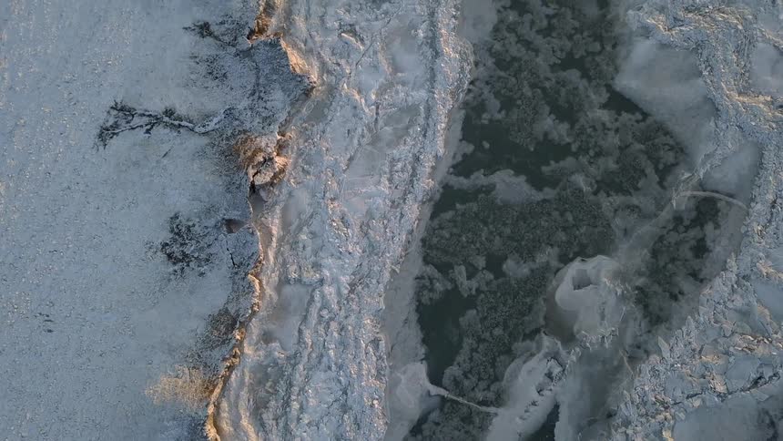 Ice and snow are covering the surface of a landscape with a river in daylight
