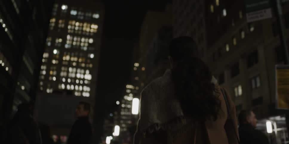A woman walks on a city sidewalk