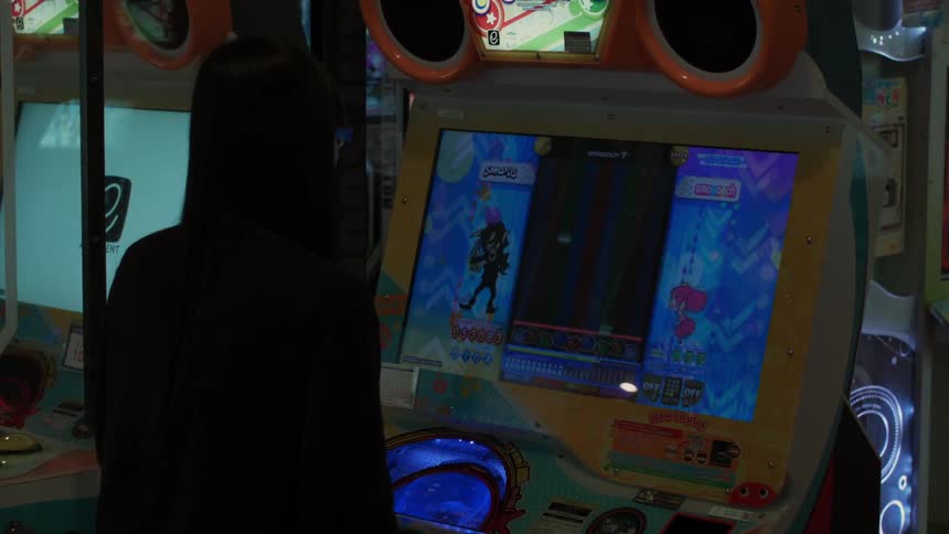 A man is playing a video game inside an arcade