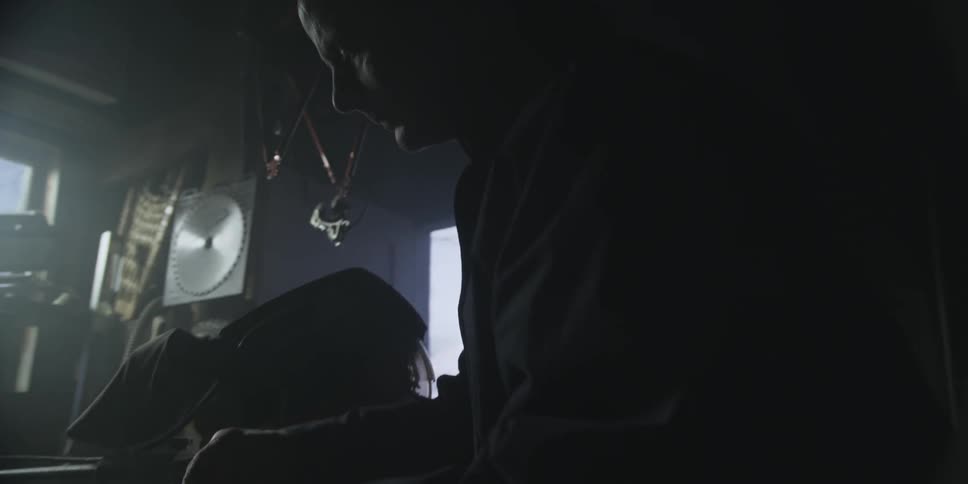 Man looking down and working on something in a dark room