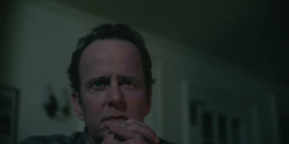 A man sitting with his hands folded as he intently watches something
