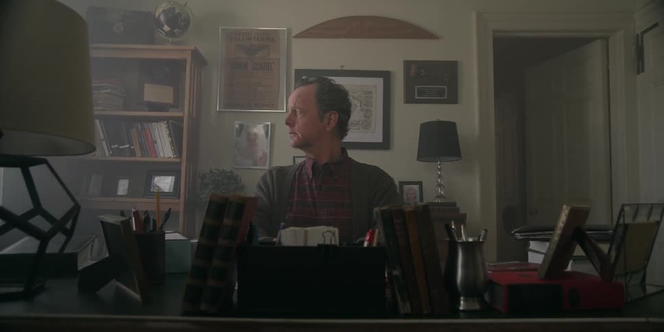 A man sitting at a desk before he gets up to look out of the window