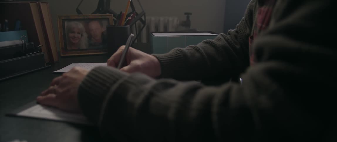 Person writing while they sit at a desk