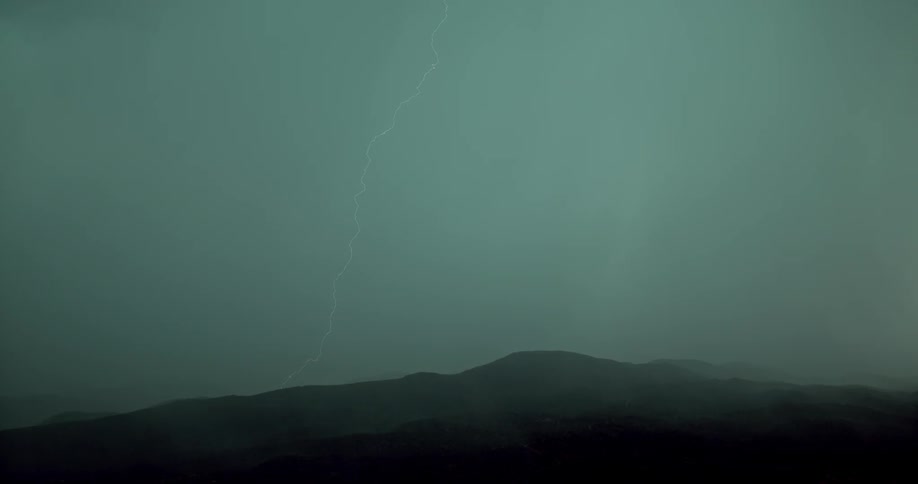 Lightning bolts in the sky over hills