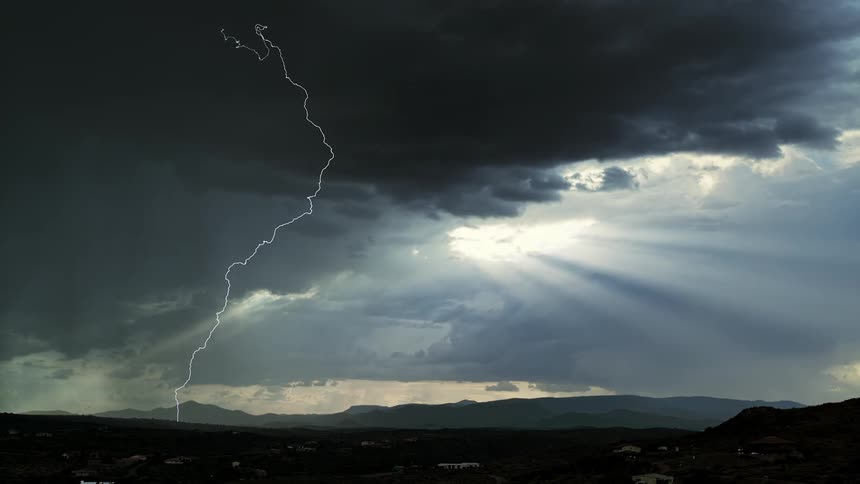A lightning storm is blowing across a desert landscape at dusk