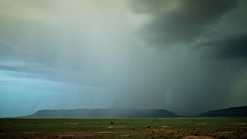 Lightning is flashing amid storm clouds as they move across a landscape in daylight