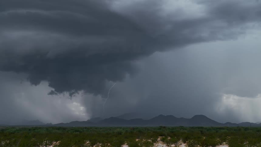 Lightning flashes in the dark sky near the mountains