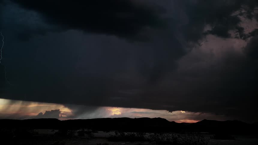 Lightning flashes over mountains at sunset