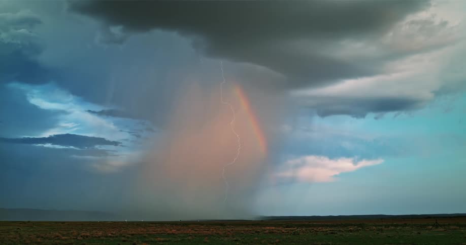 Lightning flashing in the sky above a rainbow