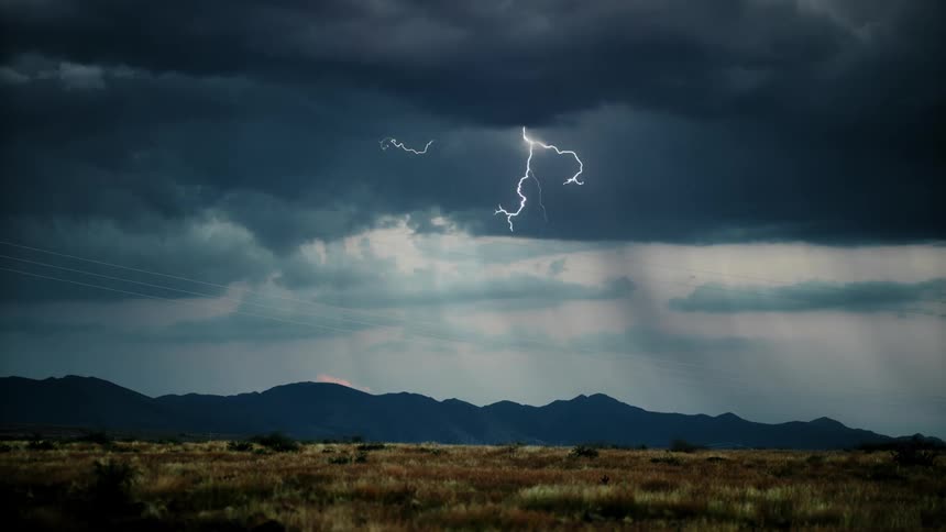 The lightning flashes and fills the fields before the mountain