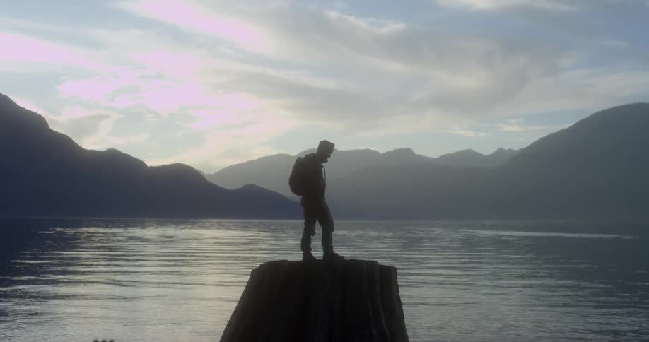 A man standing on a rock overlooking a body of water