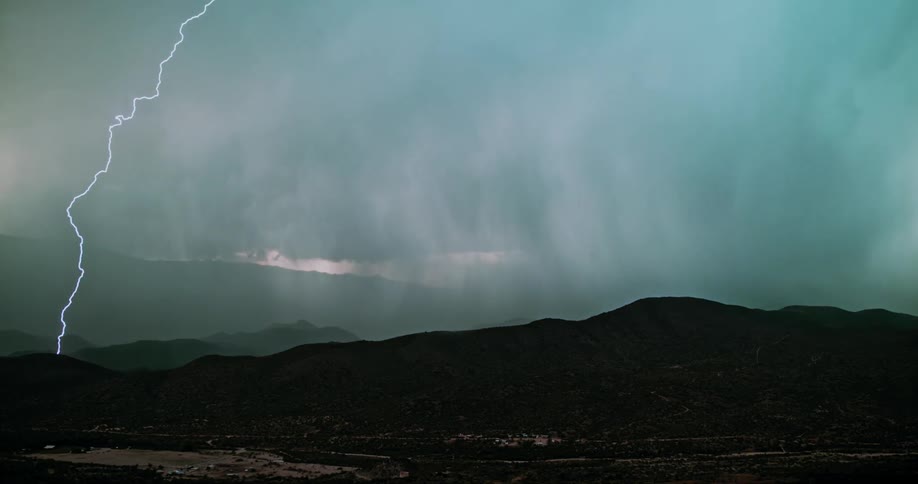 Lightning and rain flash on the hills ahead
