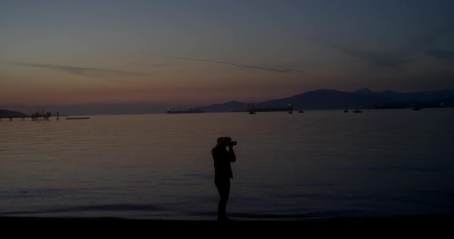 Person stands in the water as he uses his camera