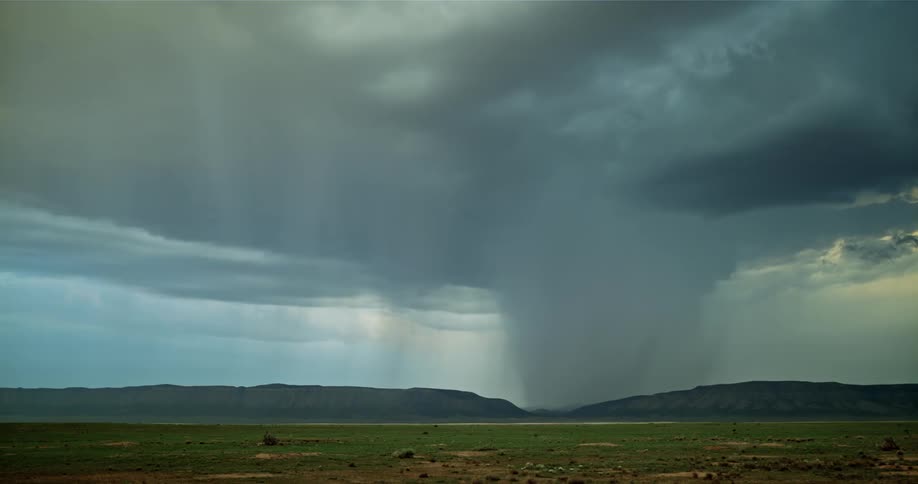 Storm clouds with rain and lightning over a field