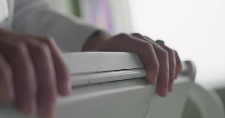 A person stands with his hands on a plastic stand