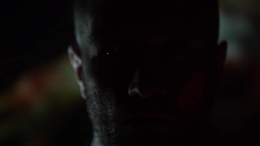 Different colored lights shine off of a man's face