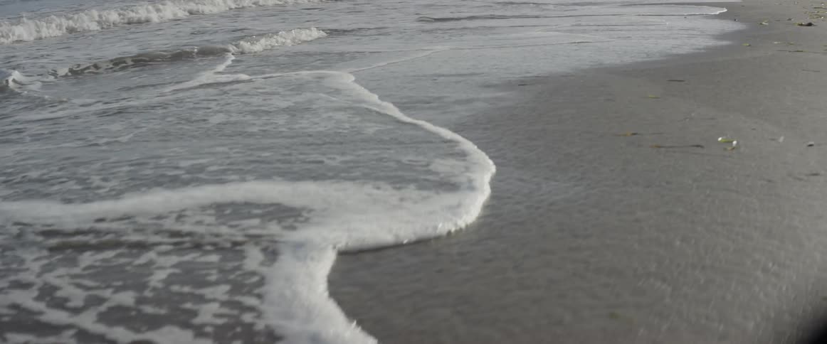 Waves are lapping the sand on a beach in daylight