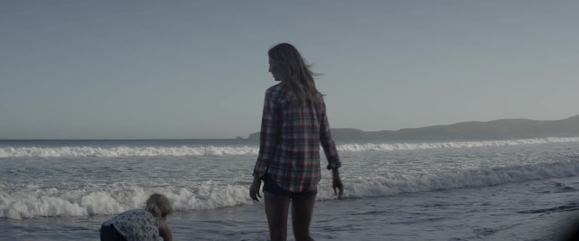 A woman talks with a young girl on the beach
