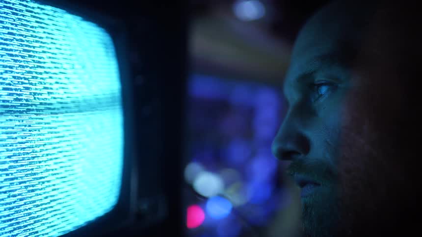 A man is standing close to a flickering television set