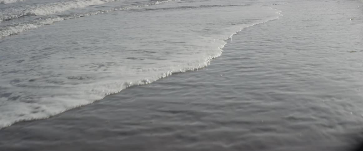 Ocean waves wash ashore a sandy beach