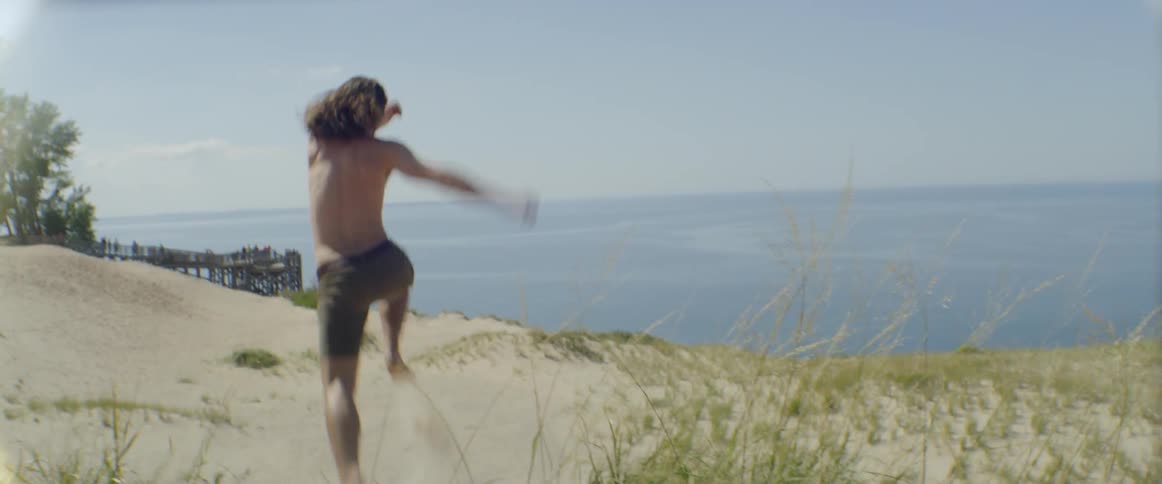 Man jumps down a sand hill at the beach