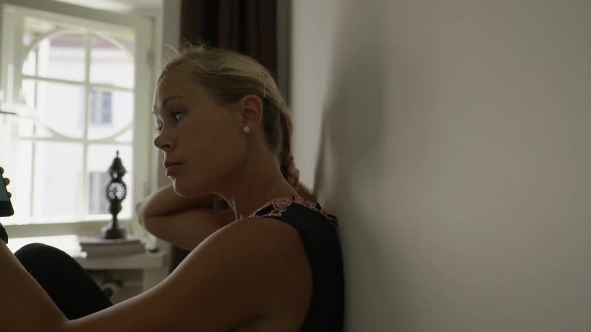 A stressed young person checks a mobile health application on her smartphone indoors.