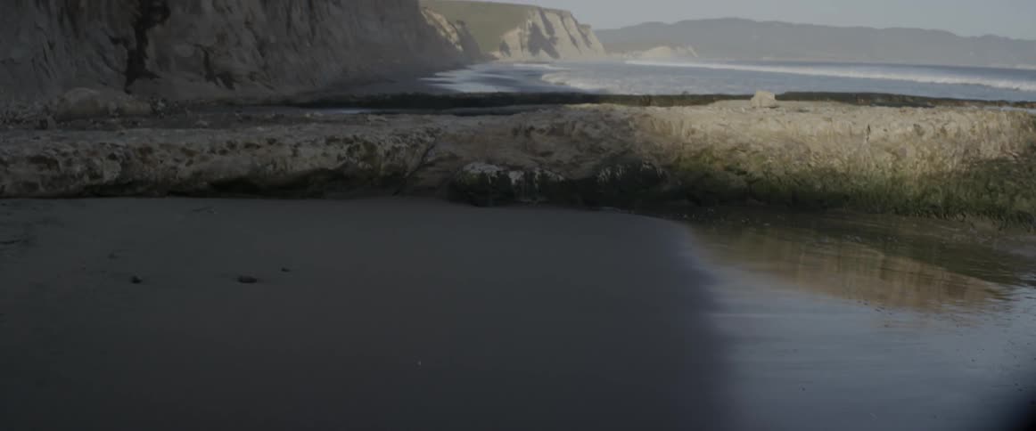 Waves are crashing against a sandbar on the coast in daylight