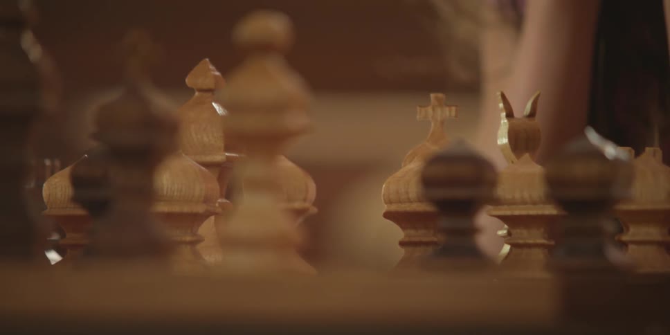 Close up of a chess board and a girl's hand as she moves a piece