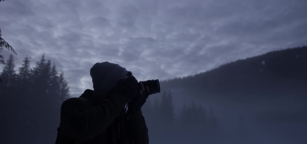 A man is photographing the hills on a cloudy day